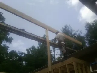 Carpenter setting a ridge beam over a new addition frame — Ice Dam Removal by Roofing Brothers in Frostburg