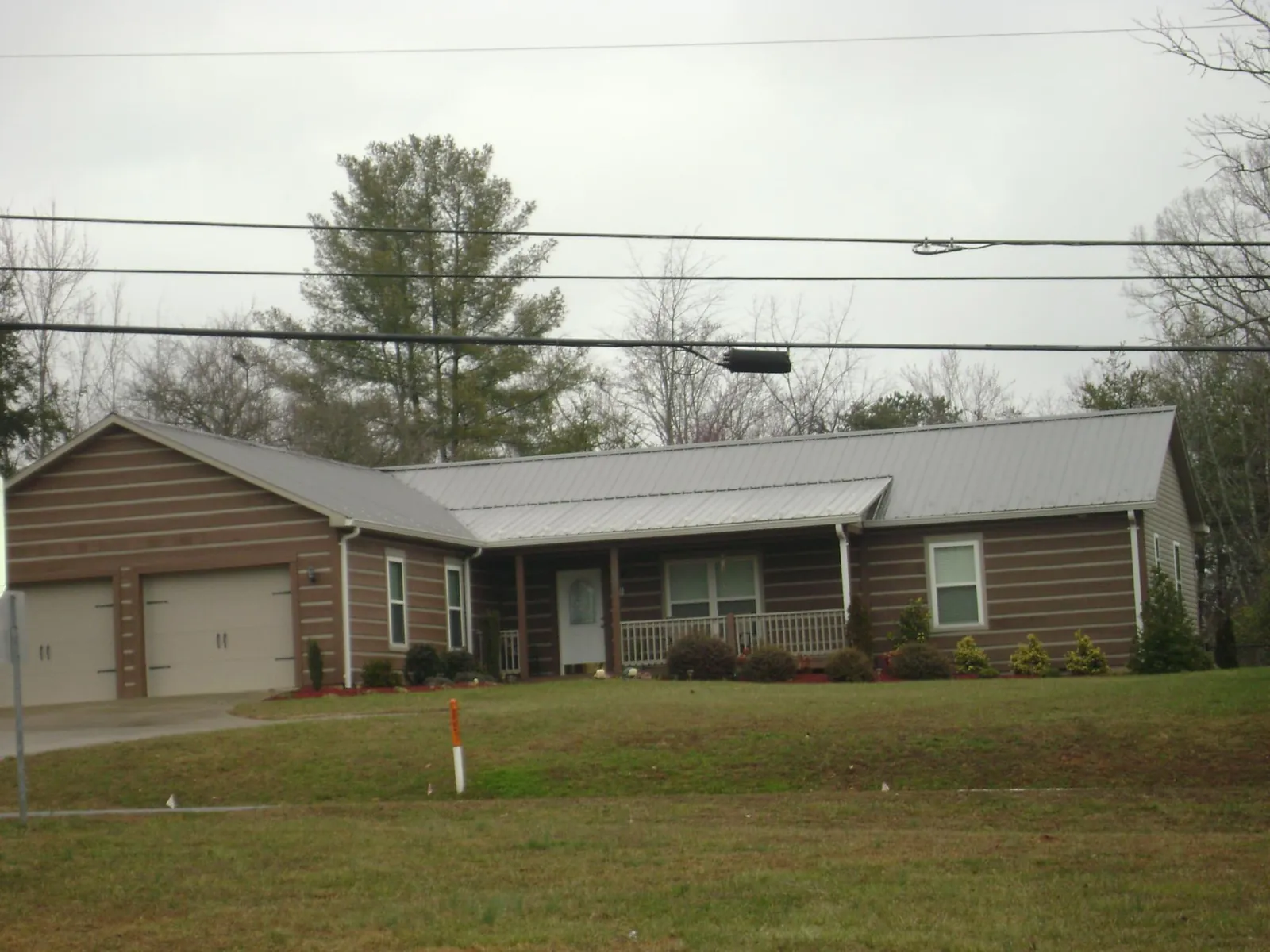 Gray metal roof on a log sided ranch home with a front porch in Frostburg