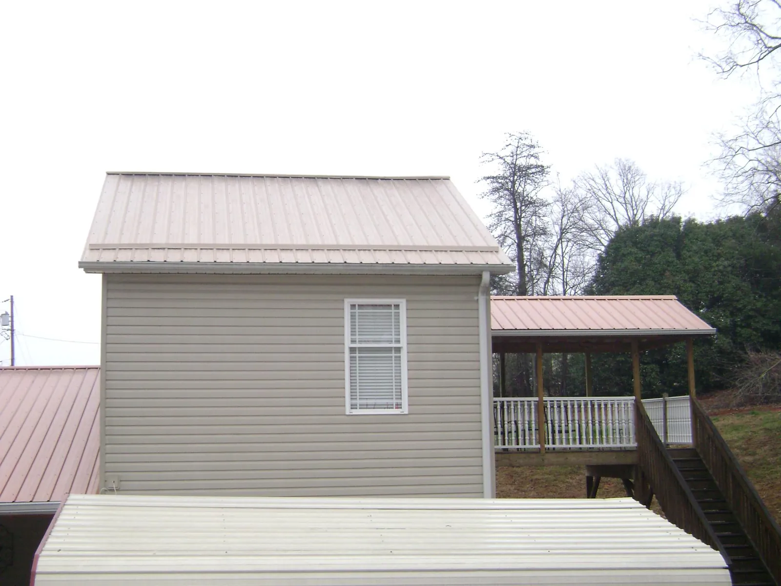 Tan metal roofs on a two story addition and attached porch, from a Roof Replacement job in Frostburg