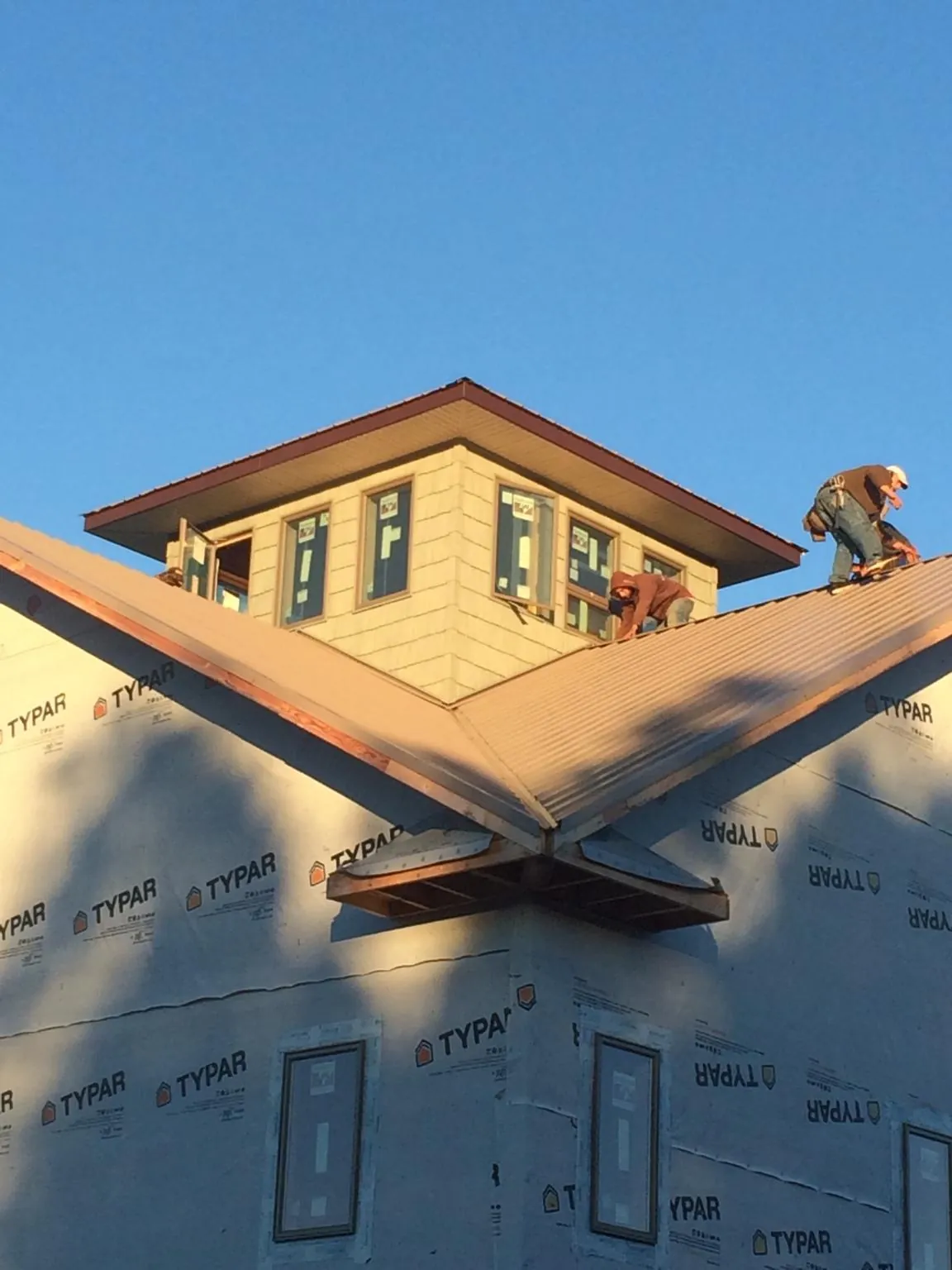 Roofers working around a rooftop cupola on a new metal roof at sunset — Roof Waterproofing in Frostburg by Roofing Brothers